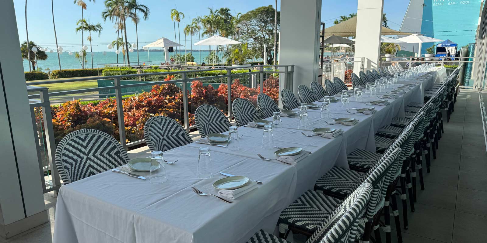 Long table set for an event with palm trees and blue skies behind.