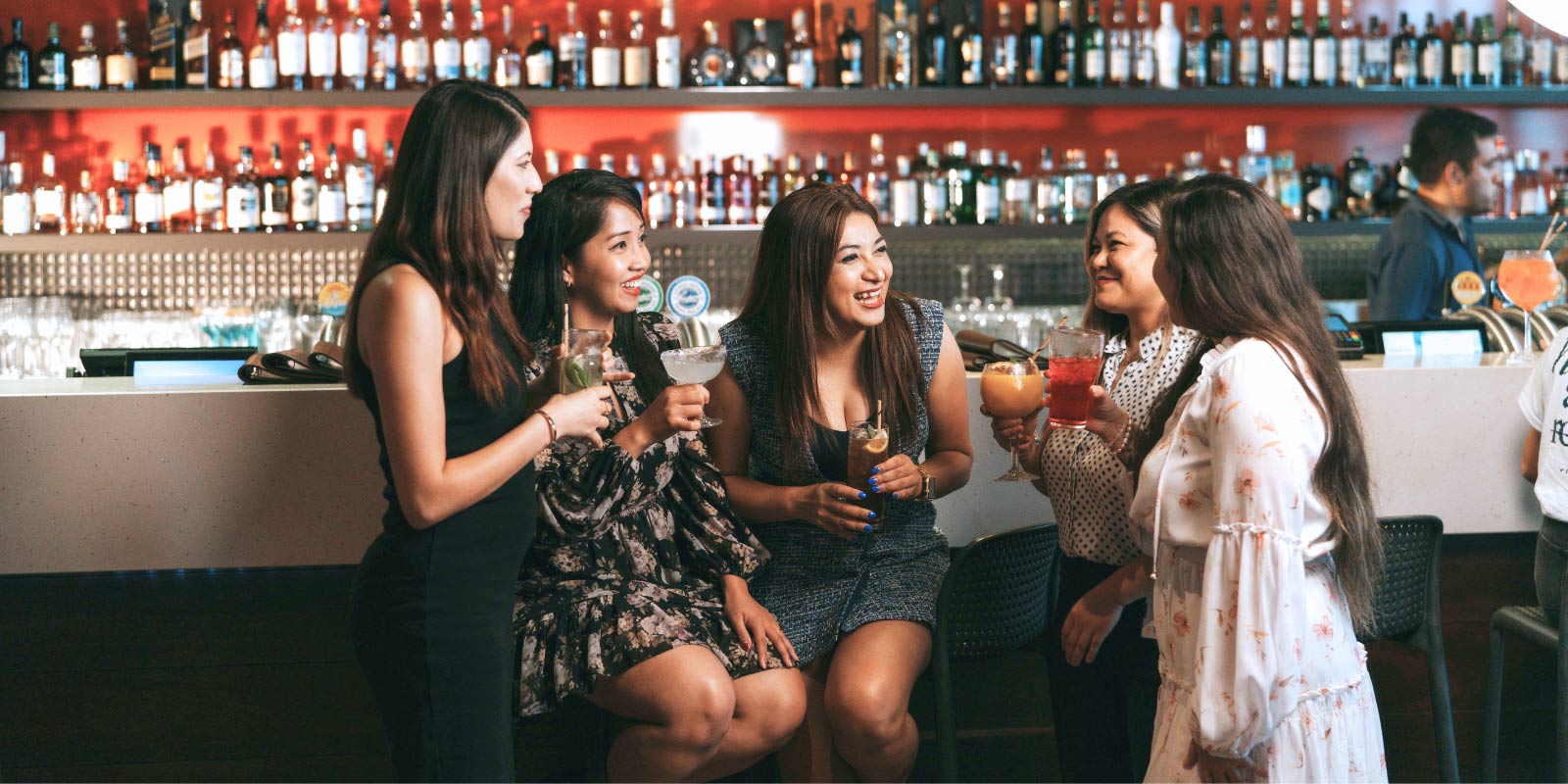 Group of friends with drinks sitting at the bar.