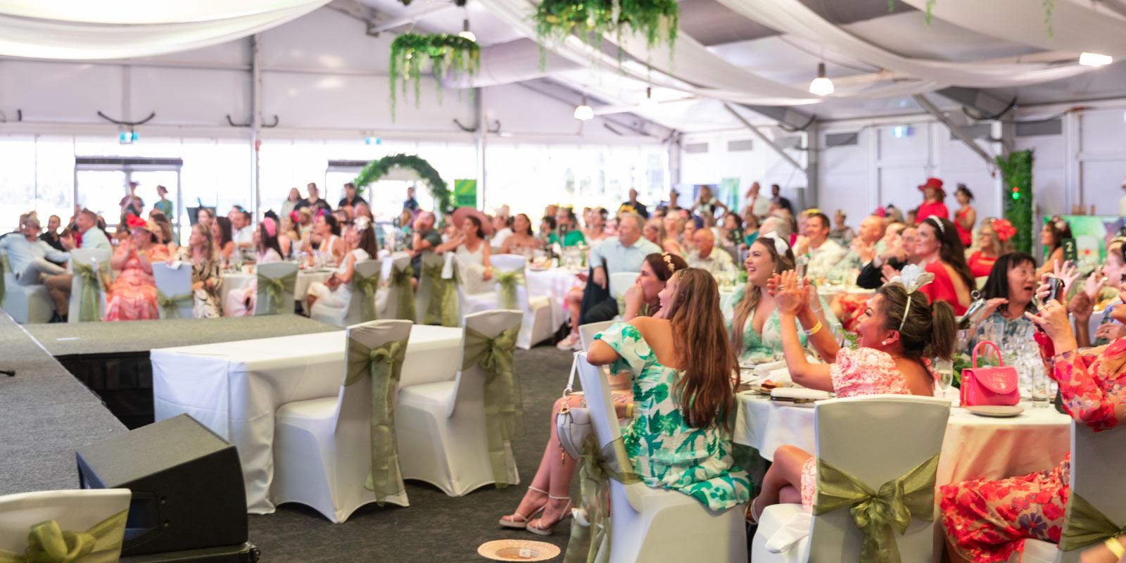 A crowd of people seated inside a tent at a formal event.