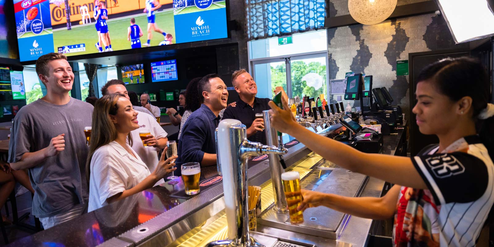 Bartender serving beer to group of friends at the bar counter.